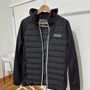 Svart jacka från McKenzie - Snygg svart jacka från McKenzie med dragkedja och quiltad design. Perfekt för kyligare dagar med sin stilrena look och bekväma passform.