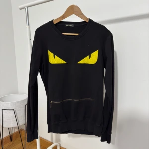 Svart tröja med gula ögon från Fendi - Cool svart tröja från Fendi med ett unikt tryck av gula ögon på framsidan. 