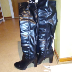 Svarta stövlar från Catwalk - Snygga svarta stövlar i skinnimitation från Catwalk. De har en hög klack och dragkedja på sidan för enkel på- och avtagning. Perfekta för höst och vinter, och ger en elegant touch till vilken outfit som helst.