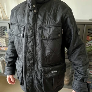 Svart quiltad jacka från Barbour - Säljer en snygg svart quiltad jacka från Barbour i mycket bra skick. Jackan har långa ärmar och praktiska fickor med knappar. Med en stilren look som funkar till det mesta. Passar både till vardags och lite finare tillfällen. Storlek 164. Kommer från ett djur- och rökfritt hem.
