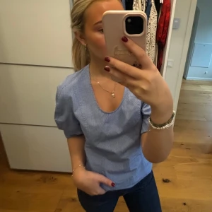 Blå rutig blus - Säljer en söt blå rutig blus med korta ärmar och u-ringning. Perfekt för vår och sommar! Blusen har en fin passform och är gjord i ett lätt och bekvämt material. Passar både till vardags och festliga tillfällen. Helt ny med lapp kvar 💙