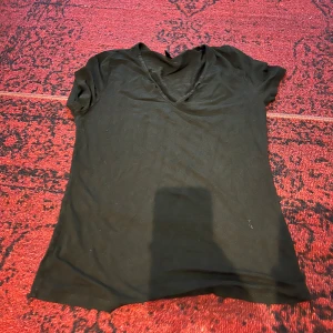 Svart v-ringad t-shirt - Säljer en enkel och stilren svart t-shirt med v-ringning. Perfekt för vardagsbruk eller att klä upp med accessoarer. T-shirten är kortärmad och i ett mjukt material som känns skönt mot huden.