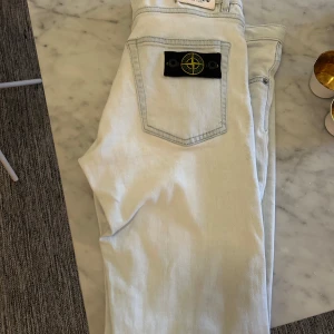 Ljusblå jeans från Stone Island - Säljer ett par ljusblå jeans från Stone Island i  bra skick. har en snygg patch på bakfickan. Dessa säljs inte längre och är svåra att få tag i jag är förmodligen billigast på marknaden av dessa storlek 170   såklart äkta 