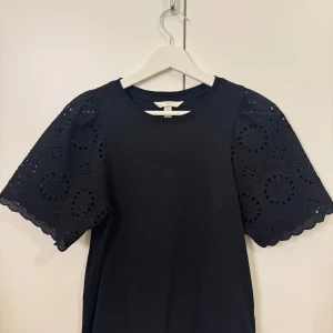 H&M T-shirt broderi anglaise - Supersöt svart t-shirt från H&M i storlek S. Den har även broderier på ärmarna vilket gör att man kan stylea den till allt. Väldigt bra skick💗💗aktiverar köp nu vid köp 
