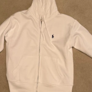 Vit hoodie från Ralph Lauren - Säljer en snygg vit hoodie från Ralph Lauren med dragkedja. Perfekt för både vardag och chill. Köpt från Zalando så den är äkta. Storlek S. Priset kan gå ner vid snabb affär. Säljer för den va för liten.