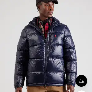 Säljer en snygg mörkblå dunjacka från Ralph Lauren. Jackan har en quiltad design med dragkedja och en liten röd logga på bröstet. Perfekt för kalla dagar med sin varma och puffiga stil. Den har långa ärmar och en huva för extra skydd mot väder och vind. Kom dm för fler bilder 