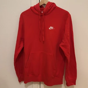 Röd hoodie | Nike - Säljer en snygg röd hoodie från Nike i storlek S. Den har en klassisk design med en känguruficka och justerbar huva. Perfekt för både vardag och träning. Den är i bra skick!