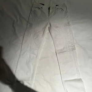 Vita skinny jeans från Dondup - Säljer ett par vita skinny jeans från Dondup i bra skick. De har en snygg och stilren design med dragkedja och knapp framtill. Perfekta för både vardag och fest! Passar till allt och ger en fräsch look.