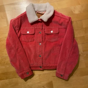 Rosa manchesterjacka från Levi's - Säljer en snygg rosa manchesterjacka från Levi's med vit teddyfoder. Jackan har en klassisk krage och knappar framtill. Perfekt för höst och vår, och den är i mycket bra skick. Storleken är barn 152 cm Supermysig och stilren för alla tillfällen!