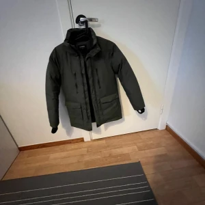 Mörkgrön vinterjacka från Everest  - Säljer en mörkgrön vinterjacka från everest i mycket bra skick. Jackan har långa ärmar och praktiska fickor framtill. Perfekt för kalla vinterdagar med sin varma och skyddande design. Passar både till vardags och utomhusaktiviteter.