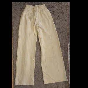 Beige vida byxor - Säljer ett par snygga beige byxor i loose fit. De är högmidjade med en elastisk midja för extra komfort. Perfekta för en avslappnad stil och passar bra till både vardag och fest. Materialet känns mjukt och skönt mot huden. Från Gina tricot, aldrig använt de💗