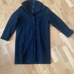 Svart kappa  från Lindex - Mysig svart teddyjacka från Lindex i storlek S. Perfekt för kyliga dagar med knäppning framtill. Jackan har långa ärmar och två praktiska fickor. Köpt förra hösten och använd vid ett fåtal tillfällen!