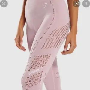 Säljer ett par ljusrosa leggings från Gymshark i använt skick (Se bilder för skick). De är högmidjade och har en tight passform, perfekt för träning. Materialet är syntetiskt och andas bra, med snygga perforerade detaljer längs benen för extra stil och ventilation.