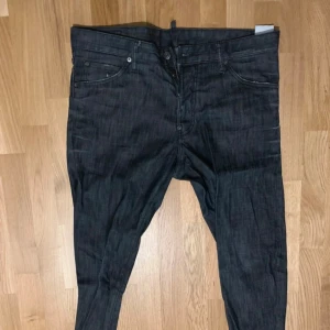 Svarta jeans från DSQUARED2 - Säljer ett par snygga svarta jeans från DSQUARED2 i storlek 52. Är i bra skick. Perfekta för både vardag och fest!  Äkta!
