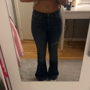 Drdenim jeans - Ett par mörkblåa bootcut jeans i mörkblå med två hål på knäna. Storlek xs/32 mid waist. Inte så använda har ej haft dem under dem senaste två åren. Inte min stil men väldigt snygga.💕