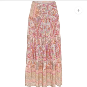 Mönstrad långkjol i bohemisk stil - Säljer en superfin långkjol med ett färgglatt, bohemiskt mönster i rosa, beige och lila toner. Kjolen har en avslappnad passform och är perfekt för sommarens festivaler eller en dag på stranden. Den är gjord i ett lätt och luftigt material som gör den skön att bära hela dagen. Den är i väldigt bra skick! 