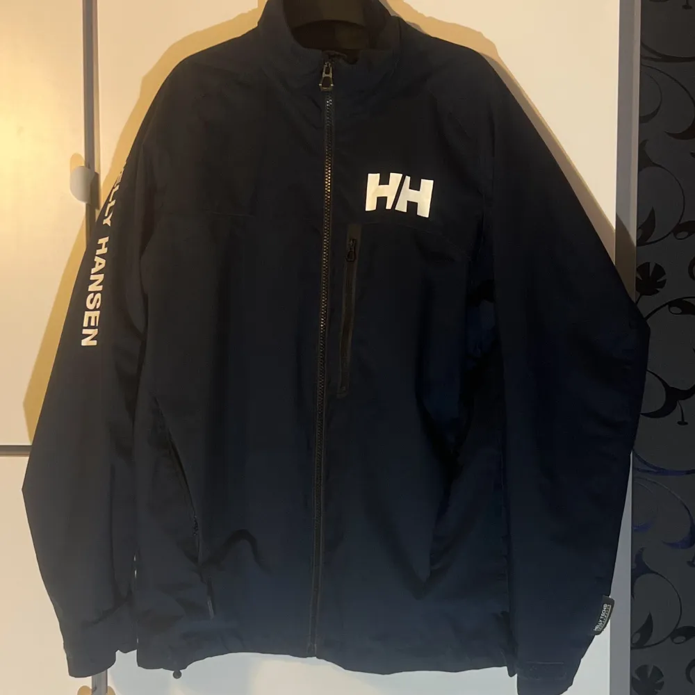 Säljer en snygg segel jacka från Helly Hansen. Den har en dragkedja framtill och logga på bröstet och ärmen. Perfekt för höst och vår med sin stilrena design och bekväma passform. Passar både till vardags och lite mer uppklädda tillfällen.. Jackor.