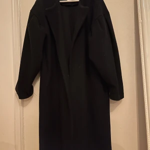 Svart kappa från Mango - Säljer en elegant svart kappa från Mango. Perfekt för höst och vinter med sin klassiska design och långa ärmar. Den är i ok skick och det saknas skärp till kappan därför säljs den billigare 🌹