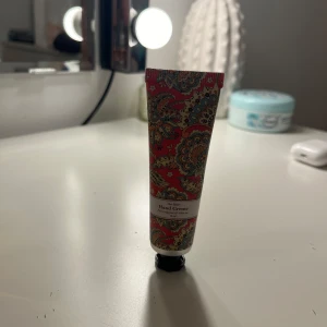 Handkräm  - En vackert mönstrad handkrämstub med orientaliskt inspirerat mönster i rött, grönt och guld. Perfekt för att hålla händerna mjuka och återfuktade. Tuben är liten och smidig att ha med i väskan.