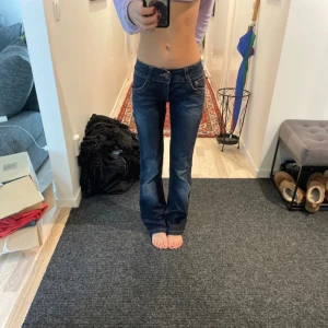 Mörkblå jeans från ONLY - Säljer ett par snygga mörkblå jeans från ONLY. De är lågmidjade och har en bootcut-stil som ger en retro vibe. Perfekta för både vardag och fest! Jeansen har klassiska fem fickor och en dragkedja med knapp framtill. De är i bra skick och redo för en ny ägare. midjemått: 35 innerbenslängd: 73