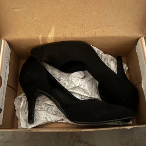 Svarta pumps från Graceland - Säljer ett par eleganta svarta pumps från Graceland i mycket bra skick. De har en spetsig tå och en stilren design, perfekta för festliga tillfällen. Skorna är gjorda i syntetmaterial och har en bekväm klack som ger en snygg siluett.