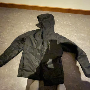 Svart Sail racing jacka - Svart Sail racing jacka  Storlek S  Dragkedjan är trasig men inte så svårt o lösa, några små hål och ett lite större som är sytt som syns på bilden också Prutas mycke vid snabb affär