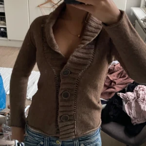 Brun kofta med knappar och bälte - Säljer en mysig brun kofta med stora knappar och ett bälte i midjan. Perfekt för höst och vinter! Den har långa ärmar och en snygg krage som ger en extra touch. Passar både till vardags och lite finare tillfällen. Superbekväm och stilren!!