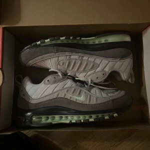 Nike Air Max 98 - Säljer ett par Nike Air Max 98 sneakers. De har en snygg design med synlig luftdämpning i sulan och klassisk snörning. Skorna är oanvända och kommer i originalkartong som har fått sig en o annan smäll. Prislapp kvar. Nypris 2095kr. 
