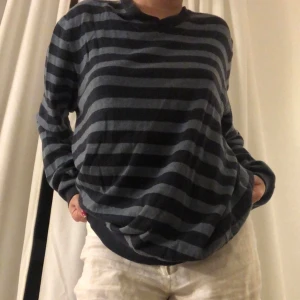 Randig långärmad tröja - Säljer en supermysig randig tröja i mörkblått och svart. Perfekt för höst och vinter med sin bekväma passform och långa ärmar. Tröjan är i bra skick och passar perfekt för en avslappnad stil. Perfekt för att mysa hemma eller en chill dag ute.