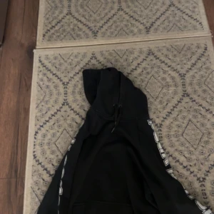 Svart hoodie från Peak Performance - Säljer en svart hoodie från Peak Performance i storlek M. Den har en klassisk design med huva och dragsko, samt vita detaljer längs ärmarna. Perfekt för en avslappnad stil eller träning. Grymt skön och passar till allt! 🖤