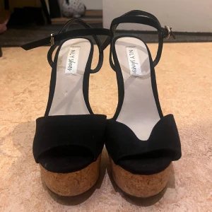 Svarta platåsandaler från NLY Shoes - Snygga svarta platåsandaler från NLY Shoes med korkklack. De har en öppen tå och justerbar rem runt ankeln. Perfekta för sommarens fester eller en utekväll. Klacken ger extra höjd och stil.