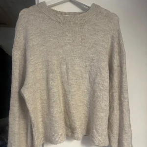 Beige stickad tröja - Mysig beige stickad tröja perfekt för kyliga dagar. Den har en enkel design med ribbstickade muddar vid ärmslut och nederkant. Passar bra till både vardag och mysiga hemmakvällar. Ett måste i garderoben för höst och vinter!