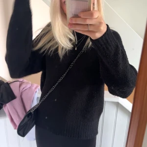 Svart stickad tröja - Mysig svart stickad tröja i bra skick. Perfekt för höst och vinter med sin varma och bekväma design. Tröjan har långa ärmar och en normal passform, vilket gör den idealisk för vardagsbruk.