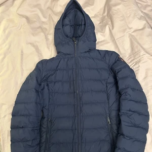 Mörkblå lättvikt dunjacka från Parajumpers - Säljer en mörkblå dunjacka från Parajumpers i super lightweight material. Perfekt som en lite tunnare vinterjacka. Den är i mycket bra skick.