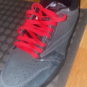Nike Air Jordan med röda snören - Säljer ett par Nike Air Jordan i grått med coola röda snören. Skorna har en snygg svart sula och är i mocka. Perfekta för både vardag och fest! De har 'Cactus Jack' detaljer på insidan och klassisk Air Jordan-logga på hälen.