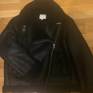 Svart skinnjacka från H&M💕 - Säljer en snygg svart skinnjacka med mjukt foder och dragkedja💕. Jackan har en fin krage som går att styla på olika sätt (se bild 3-5). Jackan är i storlek S men kan även funka för båda M-L eftersom den är lite oversized. Den är i mycket bra skick och passar perfekt till höst- och vinteroutfits. Perfekt för dig som vill ha en lite mer mysig och bekväm look. Pris går att diskutera! 