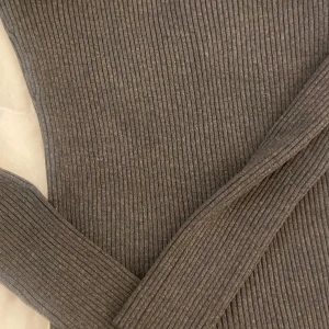 Grå ribbad tröja från H&M - Säljer en stilren grå ribbad tröja från H&M i storlek M. Tröjan har långa ärmar och en snygg detalj med pärlor längs halsringningen. Perfekt för både vardag och fest! 🖤