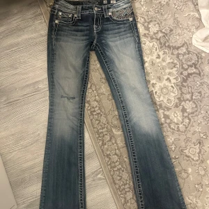 Miss me bootcut jeans - Säljer ett par snygga blå lågmidjade bootcut jeans från Miss Me. De har coola broderade detaljer på bakfickorna. Passar både till vardags och fest! Tyvärr för små för mig. Midjemått 36cm (tvärs över) Innerbenslängd 81cm och ytterbenslängd 100cm. 