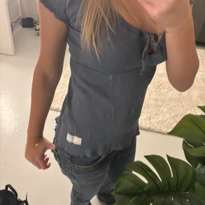 Mörkblå topp - Säljer en mörkblå topp med korta ärmar och en söt fjärilsdetalj på ryggen. Toppen har en ribbad struktur och en liten knytning framtill med fjärils detalj på ryggen. Står inte storlek men passar mig som har XS
