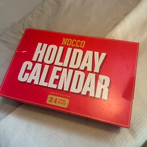Holiday Calendar från NOCCO - Säljer en limited edition NOCCO Holiday Calendar med 24 burkar inuti. Perfekt för att räkna ner till jul med en ny smak varje dag. Kalendern är röd med vit text och har en festlig design. Perfekt för NOCCO-fans som vill ha en energifylld december! Kalendern är helt oöppnad!💗