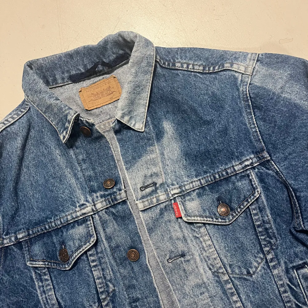 Säljer en klassisk blå jeansjacka från Levi's i bra skick. Jackan har en normal passform med knappar framtill och två bröstfickor med knappstängning. Perfekt för vår och höst!. Takit.