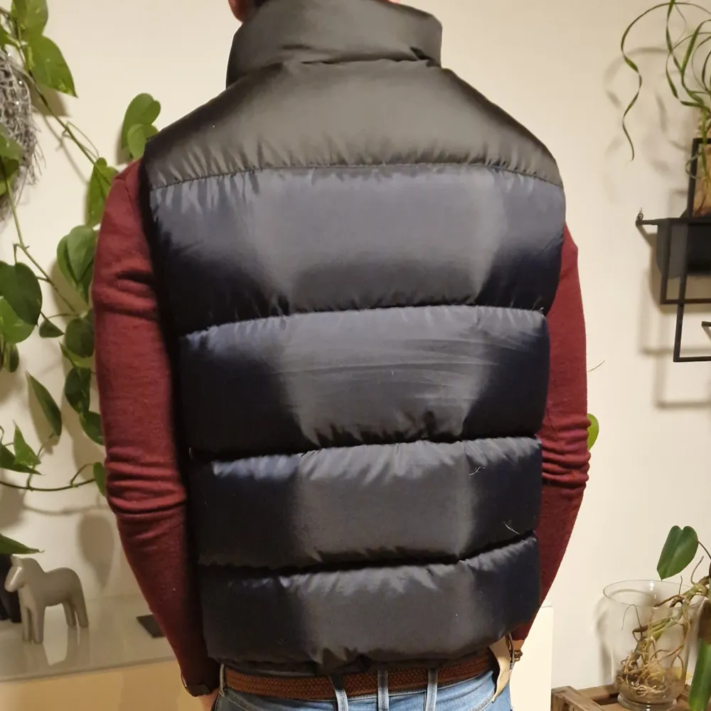 Ursnygg blå/svart, mycket varm puffer dunväst i toppskick, storlek M.  Orange logga på bröstet. Perfekt julklapp att ge bort och att hålla värmen med stil!                       Modellen är 181 cm lång och väger 74 kg, så passar dom med storlek S och M oxå.. Jackor.