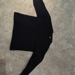 Svart stickad tröja - Säljer en svart stickad tröja i bra skick. Den har långa ärmar och ribbade muddar vid ärmslut och nederkant.  Från uniqlo 