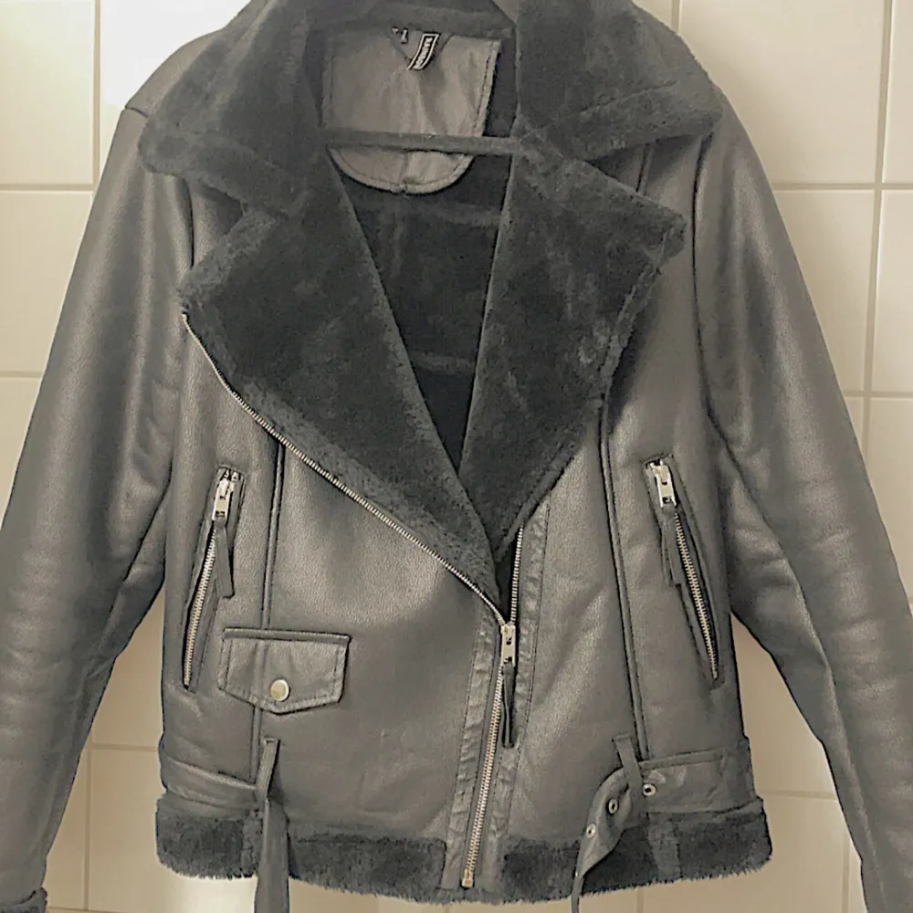 Säljer en snygg svart skinnjacka från Nelly med mjuk fejkpäls. Jackan har en cool bikerstil med dragkedjor och bälte i midjan. Perfekt för höst,vår och även vinter då den håller värmen bra!. Jackor.