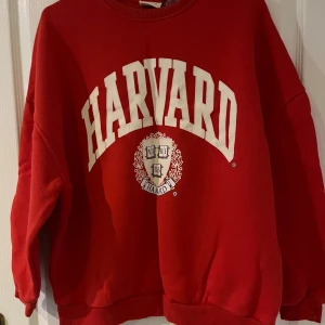 Röd Harvard sweatshirt - Säljer en röd Harvard sweatshirt i bra skick. Den har ett stort tryck med Harvard-loggan i vitt på framsidan. Tröjan är perfekt för en avslappnad stil och passar bra till både jeans och mjukisbyxor. Den är varm och skön, perfekt för kyliga dagar.