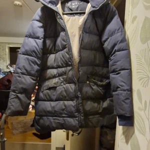 Mörkblå vinterjacka  - Säljer en mörkblå dunjacka från WYTE i bra skick. Jackan har en dragkedja framtill och två praktiska fickor med knappar. Den är långärmad och perfekt för kalla vinterdagar. Jackan har en mysig huva som skyddar mot vind och kyla. Perfekt för vintern! ❄️