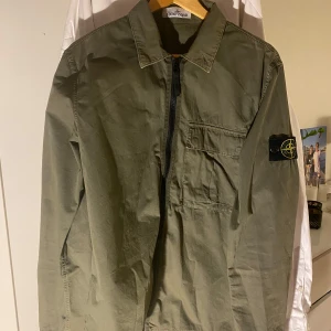 Stine island overshirt  - Säljer en grön overshirt från Stone Island i bra skick och är köpt på nk! Den har en dragkedja framtill och en bröstficka. Perfekt för höst och vår. Det finns en liten slitage på ärmen men inget man tänker på. Passar både till vardags och lite mer uppklädda tillfällen. Pris kan diskuteras 
