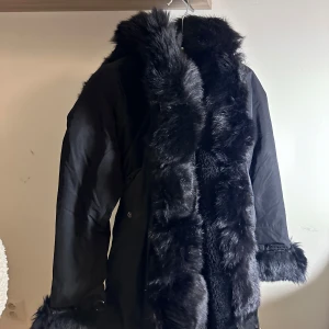 Garoff - Svart pälsjacka - Säljer en svart pälsjacka med fluffigt foder inuti och äkta svart päls vid ärmslut och krage. Perfekt för kalla vinterdagar, Kan spännas för att få en mer figursydd look eller stängas med knapparna. 🖤