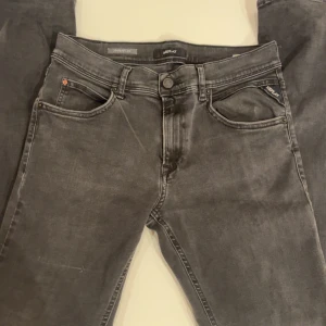 Grå jeans från Replay - Säljer ett par grå Replay jeans i mycket bra skick. De har en slim passform och är perfekta för både vardag och fest. Klassisk femficksdesign med knapp och dragkedja. Superbekväma och stilrena. Har en liten slitning som man ser på första bilden på höger ben. Pris ej hugget i sten. Har du frågor är de bara o fråga!