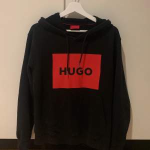 Säljer en snygg svart hoodie från Hugo med en stor röd logga på bröstet.